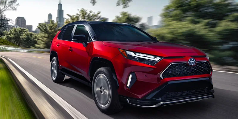 A red 2025 Toyota RAV4 Plug-in Hybrid Driving down the road.