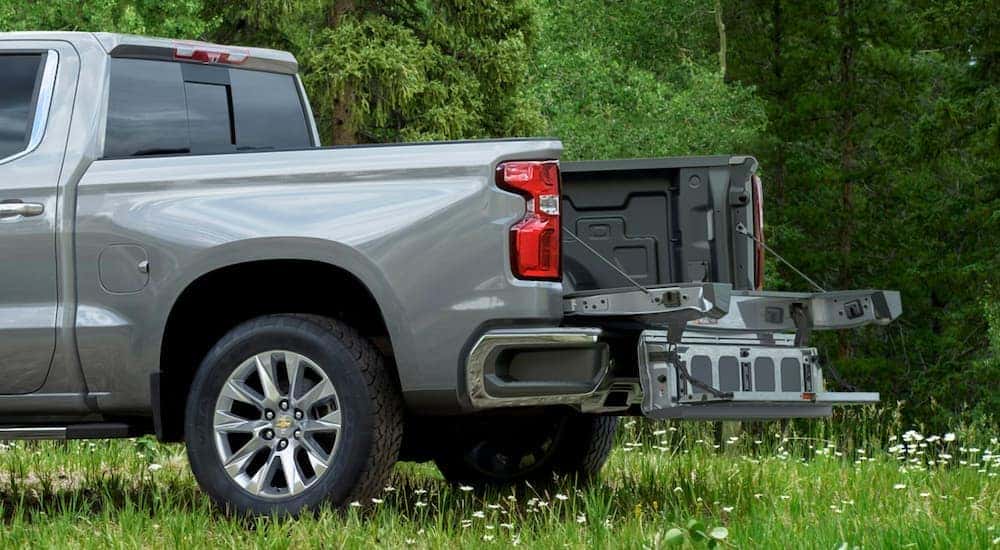 The step of a grey 2021 Chevy Silverado 1500's multi function tailgate is open in a field near Lexington, KY.