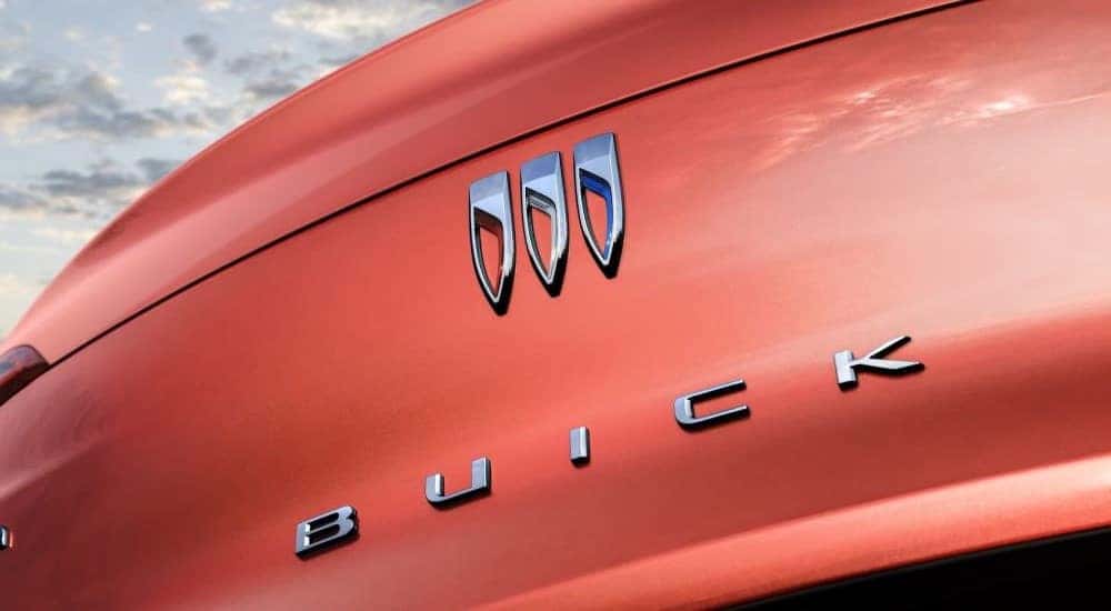 A close up shows the Buick badge on an orange 2024 Buick Envista ST.