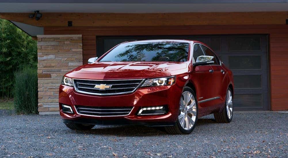 A red 2020 Chevy Impala is shown parked near a garage.