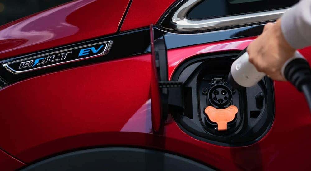 A red 2021 Chevy Bolt EV is charging in a close up.