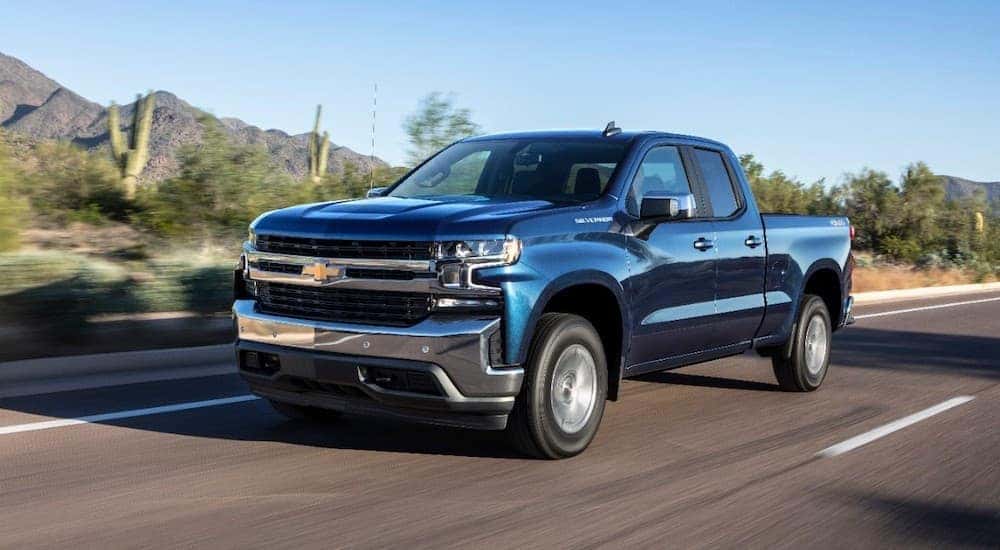 A blue 2019 Chevy Silverado 1500 is driving on a highway through a desert.