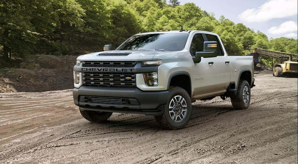A white 2020 Chevy Silverado 2500HD is driving on a construction site.