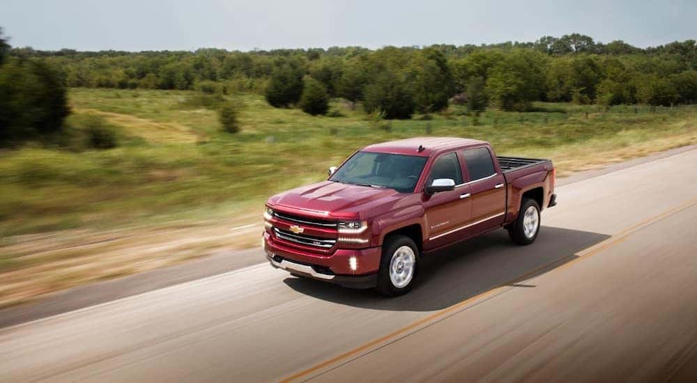 A red 2018 Chevy Silverado 1500 is shown driving on a highway.
