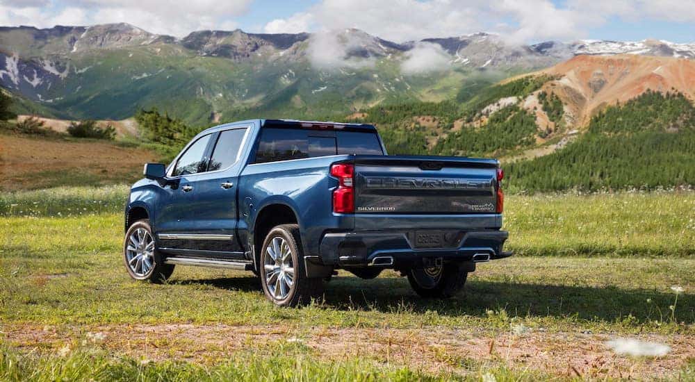 A blue 2024 Chevy Silverado 1500 High Country is shown from the rear at an angle.
