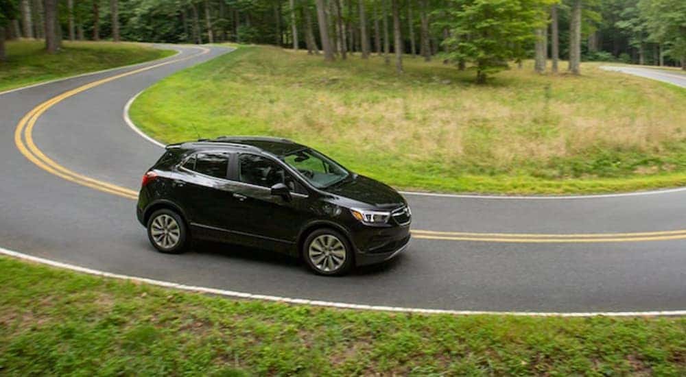 A black 2021 Buick Encore is shown from the side while rounding a bend.