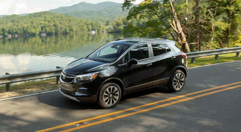 A black 2021 Buick Encore is shown from the front at an angle while driving on a lakeside road.