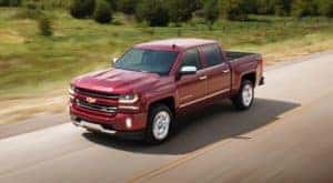 A red 2018 Chevy Silverado 1500 is shown driving on an open road after leaving a used truck dealer in Lexington.
