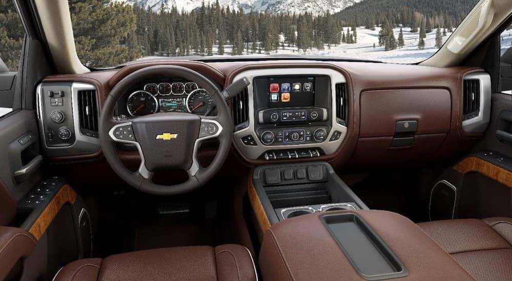 The dashboard and brown leather interior are shown in a used Chevy Silverado 1500.