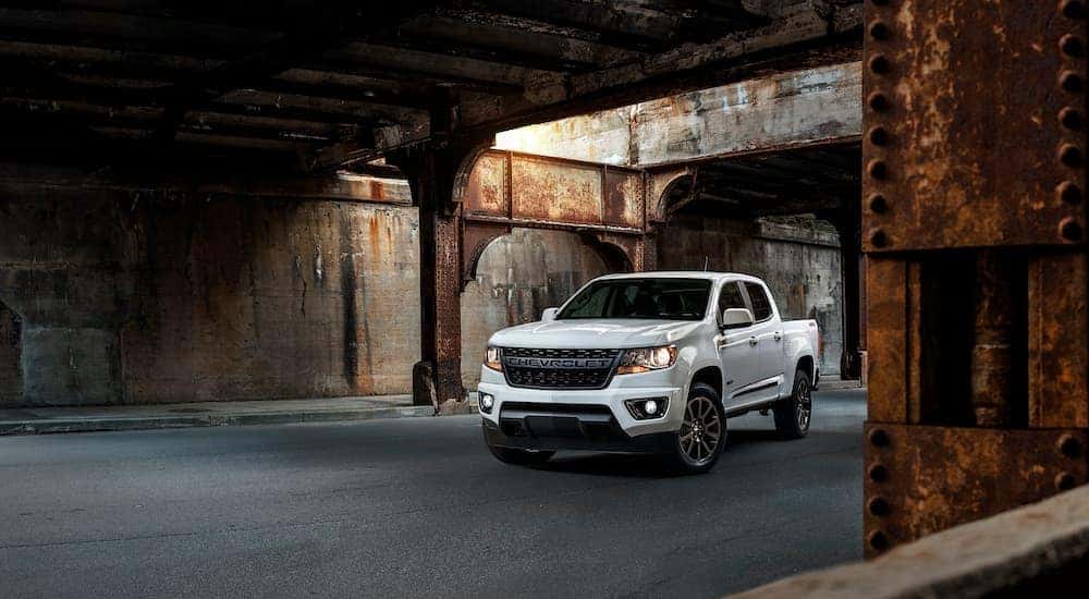 A white 2019 Chevy Colorado RST diesel is parked under a rusty bridge.