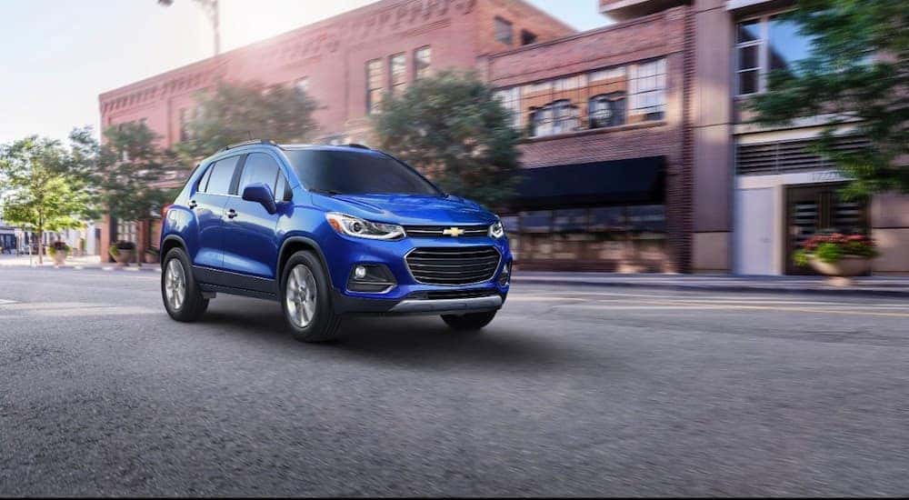A blue 2017 Chevy Trax is driving on a down town street near Lexington, KY.