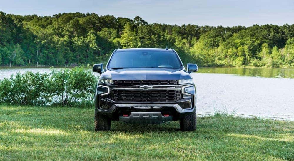 A gray 2021 Chevy Suburban is shown from the front parked in front of a lake.