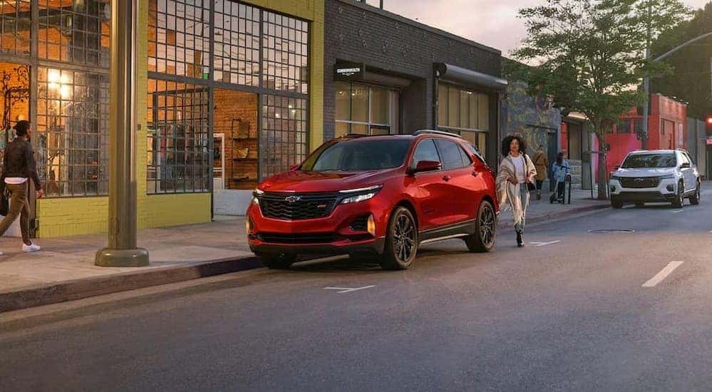 A red 2024 Chevy Equinox RS is shown parked on a city street close to a Chevy dealer near Maysville.