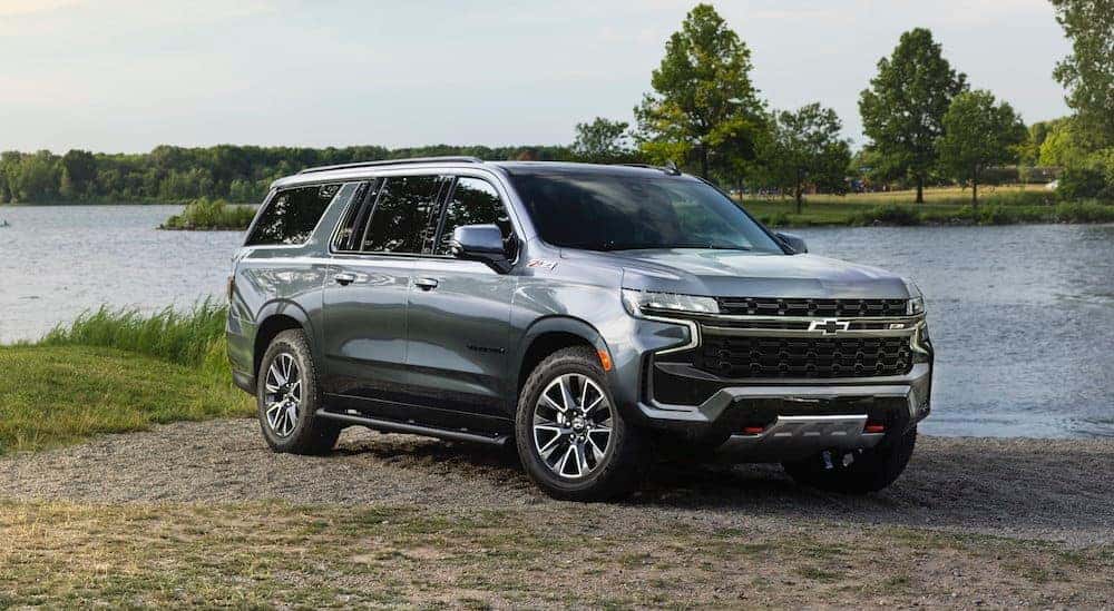 A grey 2021 Chevy Suburban is parked in front of a lake.
