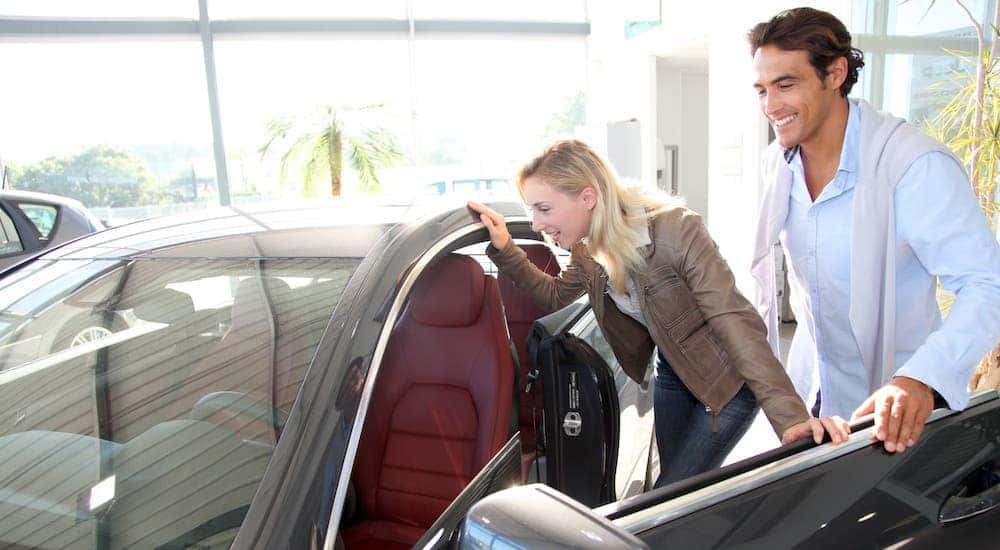 A couple is looking at a car in a used car dealership showroom.