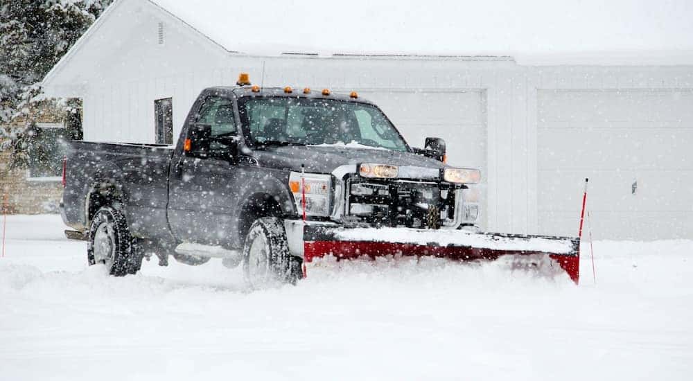 A black truck is being used to plow snow.