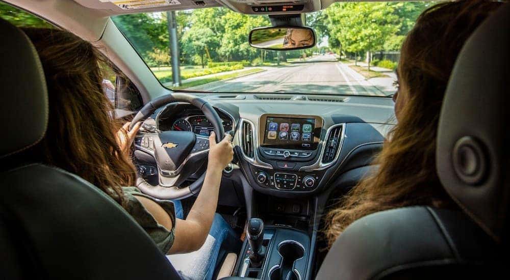 A teen girl is behind the wheel of a 2018 Chevy Equinox, which is popular among used vehicles for sale.