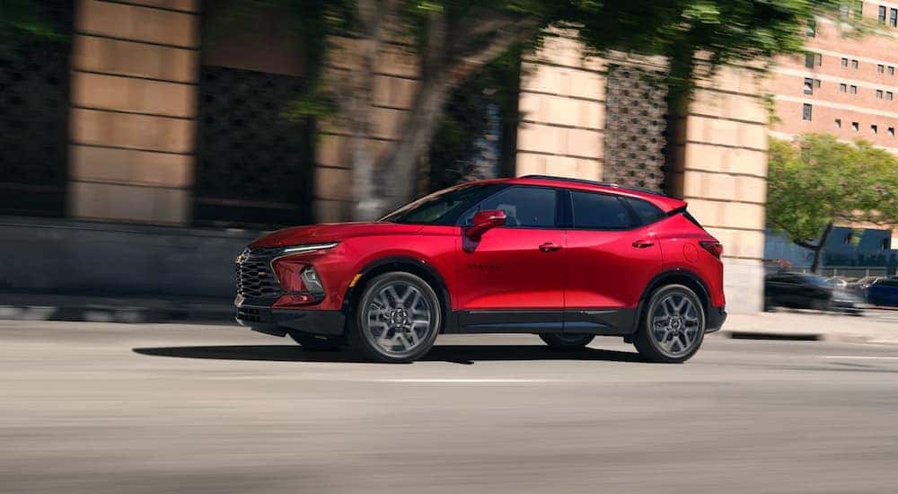 A red 2023 Chevy Blazer RS is shown driving on a city street.