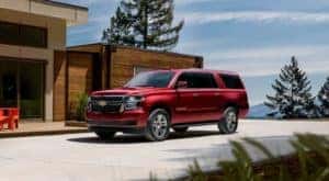 A red 2020 Chevy Suburban is shown from the front parked in front of a modern house after leaving a Lexington used car dealer.