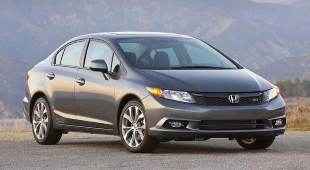 A grey 2013 Honda Civic is parked in front of a mountain and is popular among used cars priced under 10k.