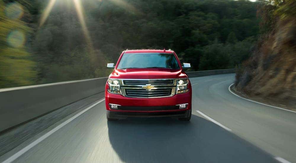 A red 2020 Chevy Tahoe is driving around a corner on a mountain road.