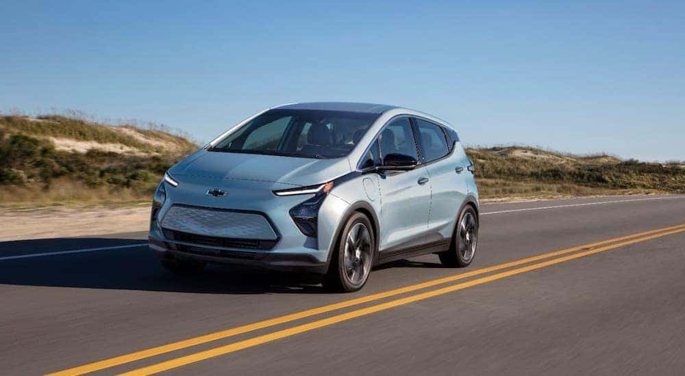 A pale blue 2022 Chevy Bolt EV is driving on a highway.