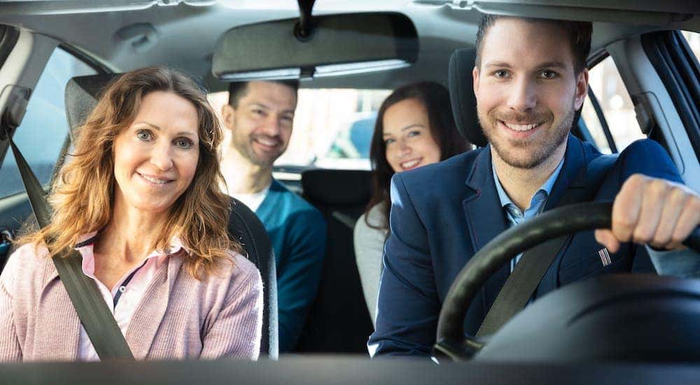 A group of professionals are shown inside a car from the front.