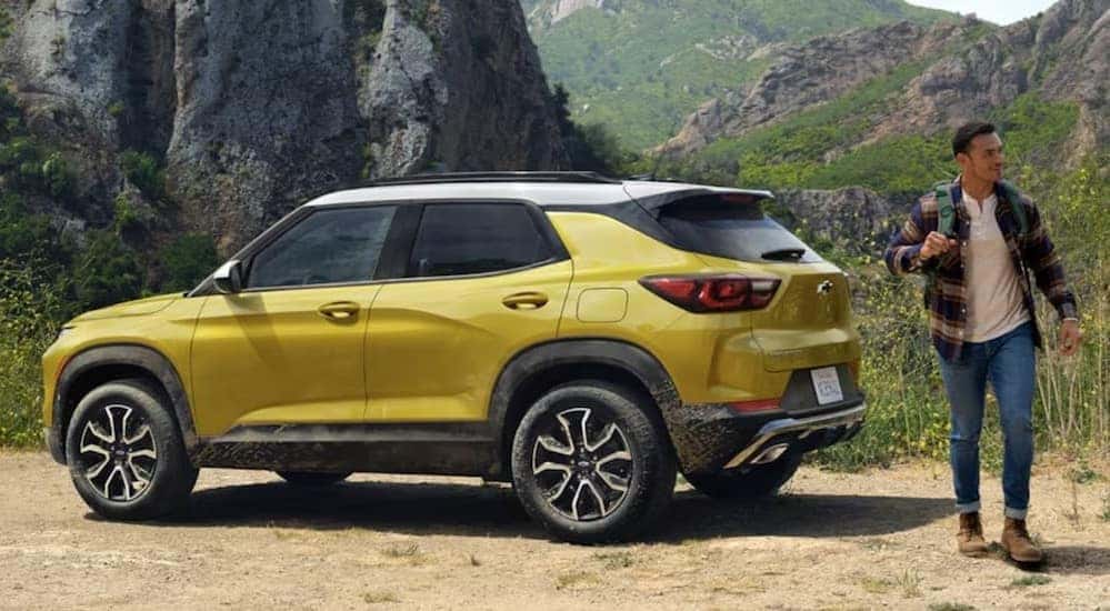 A yellow and white 2024 Chevy Trailblazer is shown parked near a person with a backpack.