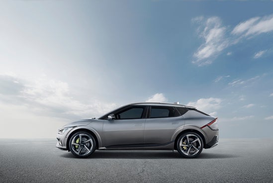 Kia EV6 Electric is parked on a smooth, open surface under a partly cloudy sky.