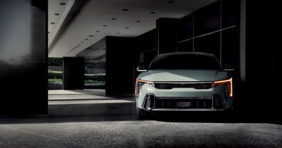 2025 Kia K4 with distinctive LED headlights is parked in a shadowy, contemporary building entrance, 