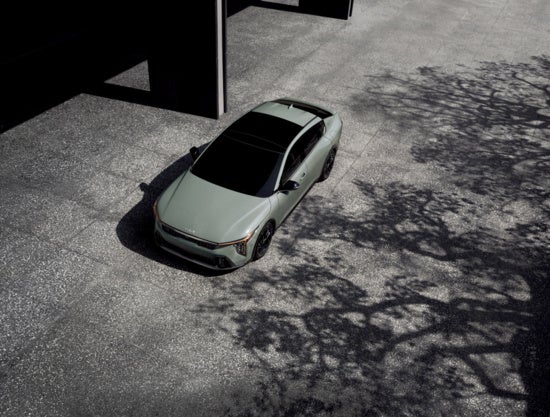 Stunning Kia K4 is parked on a textured concrete surface.