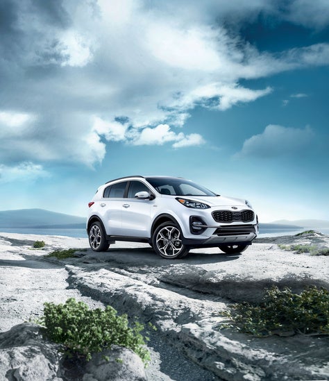 Certified Pre-owned Kia Sportage parked on a rocky terrain under a dramatic, cloudy sky