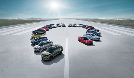 Kia lineup arranged in a large circle on a wide, open runway under a bright, clear sky.