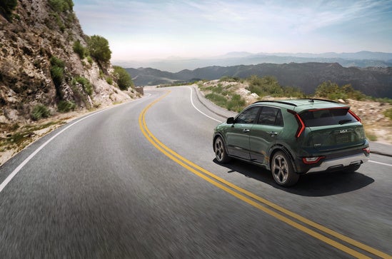 Kia EV SUV is driving along a winding mountain roads.