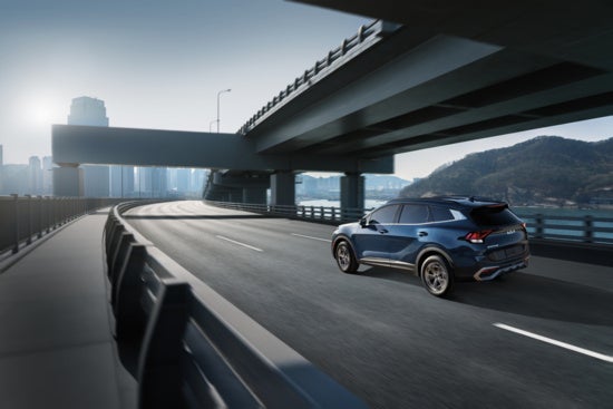 2025 Kia Sportage driving through city in blue.