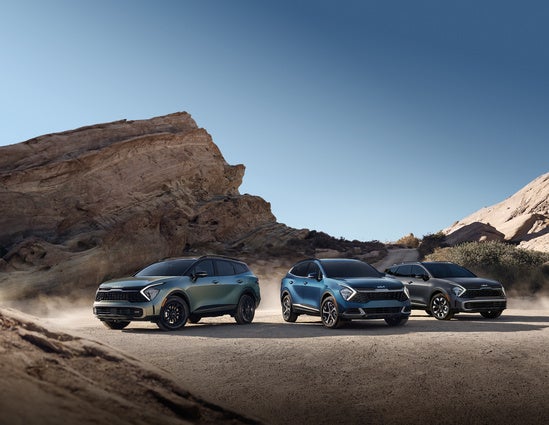 Three sleek SUVs are parked on a dusty road. 