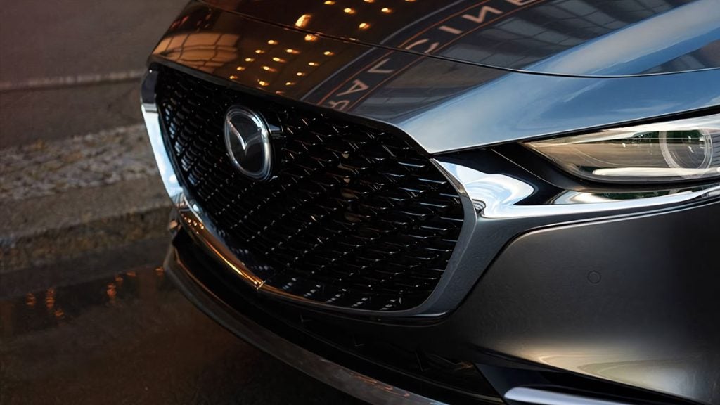Front grille of a Mazda, showcasing its sleek design and distinctive brand emblem.