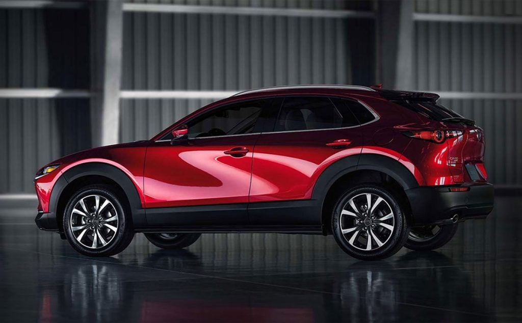A red Mazda CX-30, a compact SUV, parked against a neutral background showcasing its sleek design.