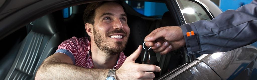 A man smiling while seated in a car, conveying a sense of happiness and contentment.