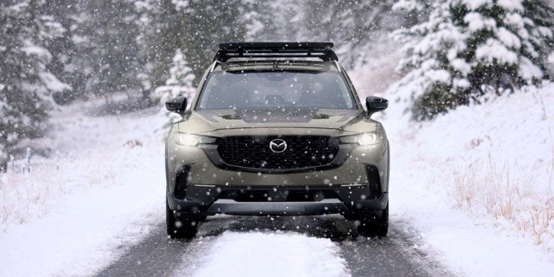 A Mazda CX-50 traversing a snow-covered road, demonstrating its all-weather driving abilities.