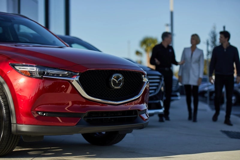 A Mazda parked outside a dealership, showcasing its sleek design and modern features.