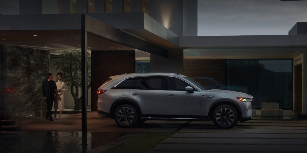 Mazda CX-90 parked in front of a sleek, modern home with large windows and a minimalist design.