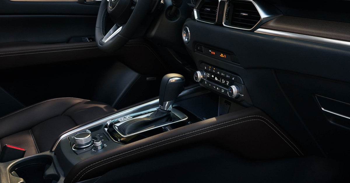 Close-up of the center console and gear selector with stitched leather trim and climate controls.