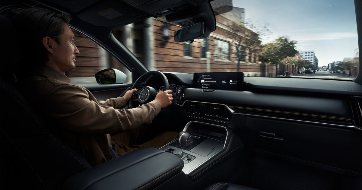 Driver inside Mazda SUV with infotainment screen and dashboard view