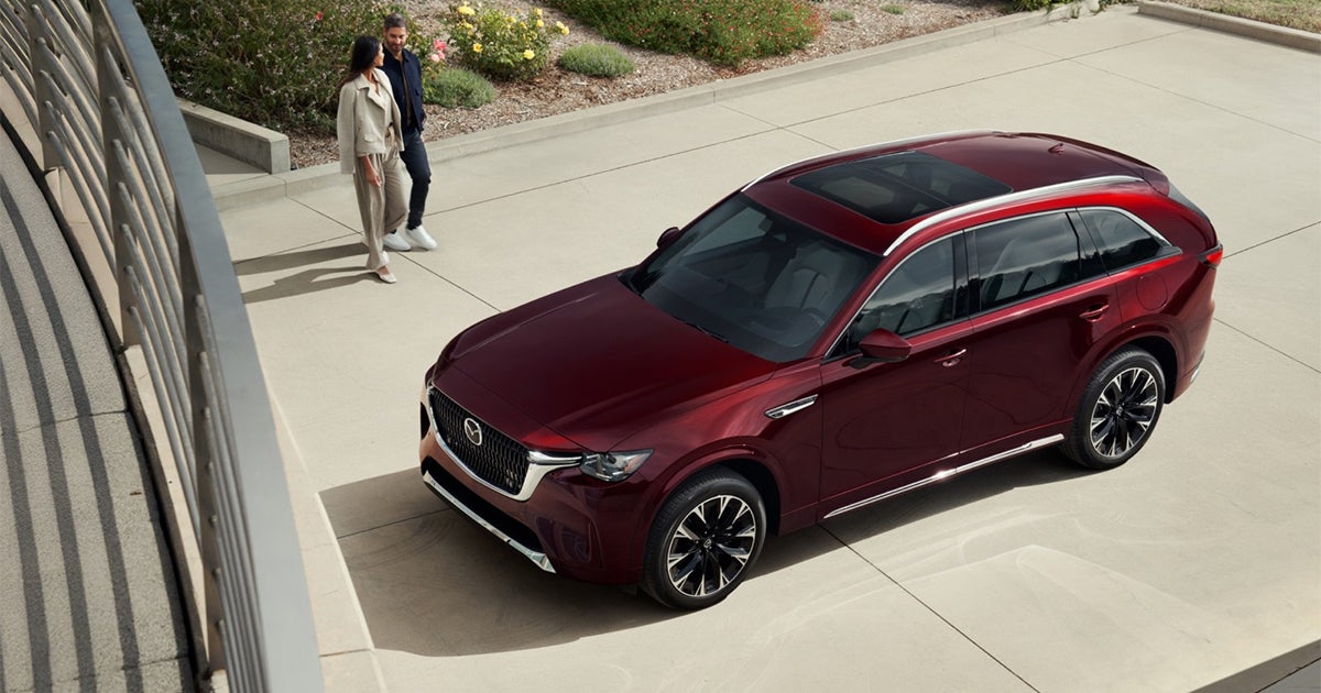 Red Mazda CX-90 SUV viewed from above with couple walking nearby