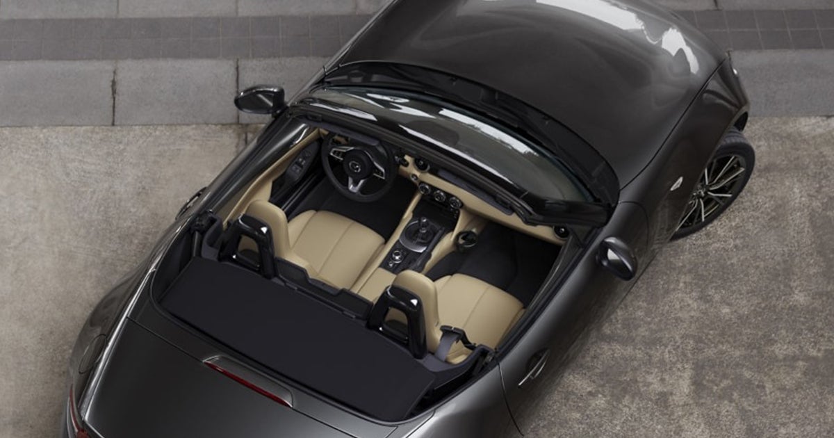Black convertible with tan interior, roof down, showing the two seats, steering wheel, and center console from above.