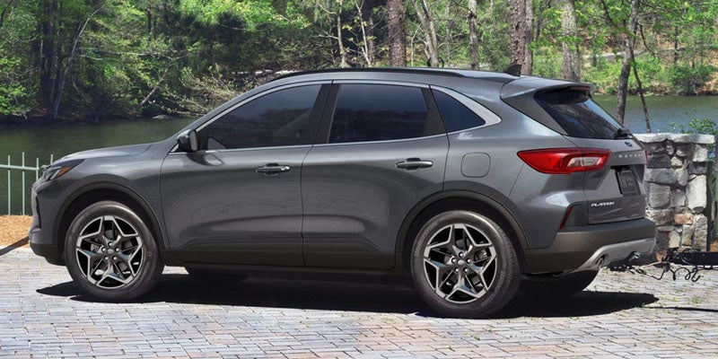 Gray Ford Escape SUV parked on a brick patio with a lake and trees in the background.