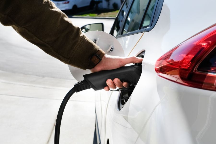 person charging and filling up hybrid car