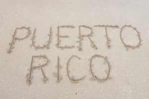 Letters PUERTO RICO carved in soft white sand of tropical beach in Puerto Rico
