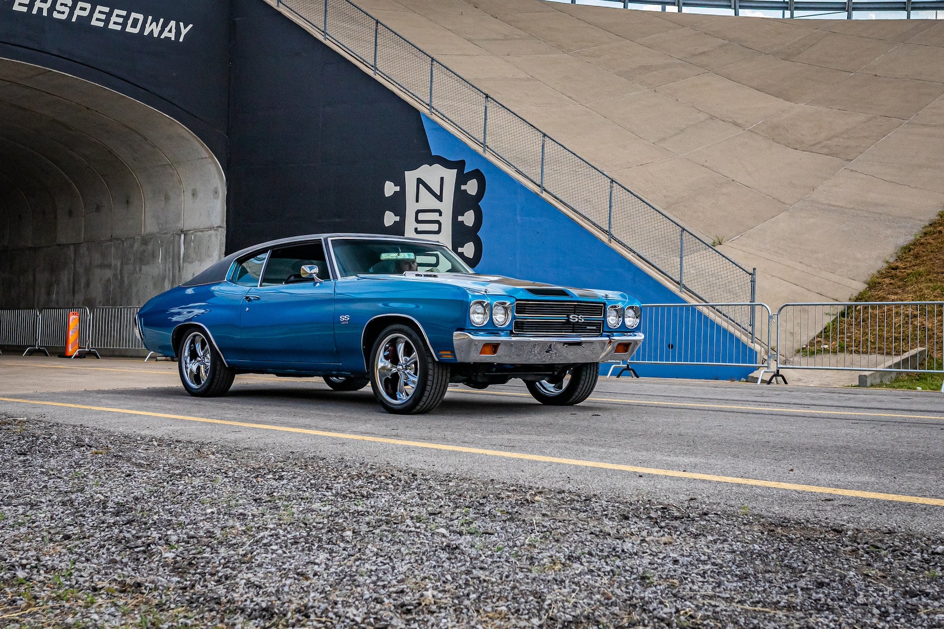 Wide angle front corner view of a 1970 Chevrolet Chevelle Malibu SS454 coupe driving on a road leaving a local car show.